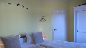 Ein Zimmer mit zwei Betten, einer Tür, einer Wandleuchte und einer Wanddekoration.