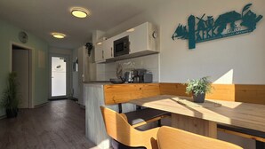 Una cocina moderna con microondas, estufa y lavamanos. Hay un banco de madera y una mesa con una planta en maceta.