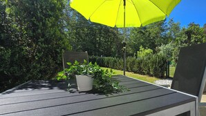 Un patio con una mesa, sillas, una planta en maceta y un paraguas amarillo.