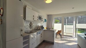 Una cocina moderna con armarios blancos, un microondas y un ventanal amplio.