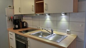 Una cuina moderna amb un doble recipient, electrodomèstics d'acer inoxidable i armaris de fusta.