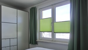 Ein Schlafzimmer mit einem Bett, einem Kleiderschrank und einem Fenster mit grünen Jalousien.