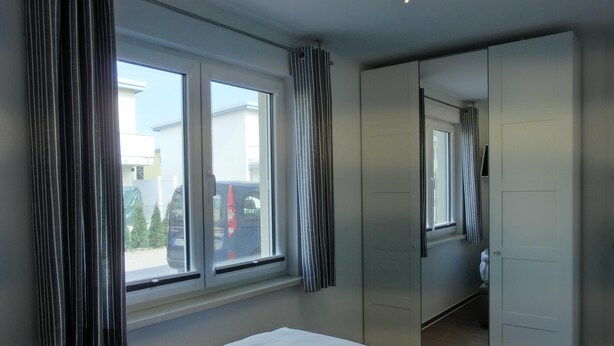 A hotel room with a bed, a wardrobe, and a window with curtains. - 2-zimmer-fewo für 2 Pers. im EG (Graal-Müritz)