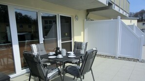 An outdoor patio with a table set for four, surrounded by wicker chairs. - 2-zimmer-fewo für 2 Pers. im EG (Graal-Müritz)