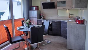 A modern kitchen with a dining area, equipped with a refrigerator, coffee maker, and toaster. - 2-zimmer-fewo für 2 Pers. im EG (Graal-Müritz)