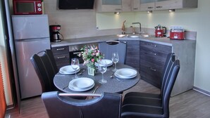 A compact kitchen with modern appliances, a dining area with a round table and chairs, and a small island with a sink. - 2-zimmer-fewo für 2 Pers. im EG (Graal-Müritz)