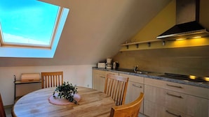A kitchen with a skylight, wooden cabinets, a dining table with chairs, and a plant. - Große, Komfortable 3 Zimmer-maisonette-ferienwohnung für 5 Personen (Graal-Müritz)