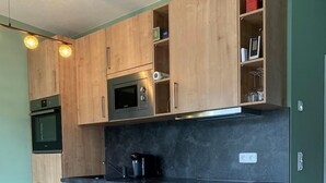 Een moderne keuken met houten kastjes, een zwart aanrecht en ingebouwde apparatuur.