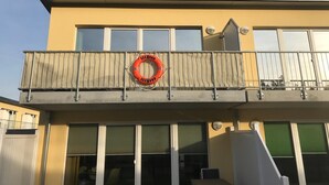Een gebouw met een balkon, een reddingsboei en een raam met uitzicht.