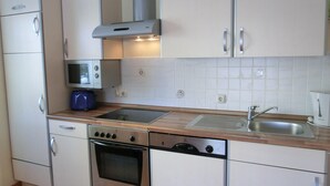A compact kitchen with a microwave, oven, dishwasher, and a sink.