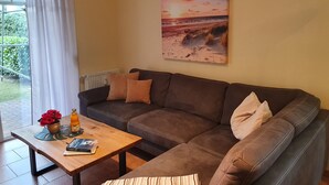 A living room with a brown leather sofa, a wooden coffee table, and a painting of a beach scene.