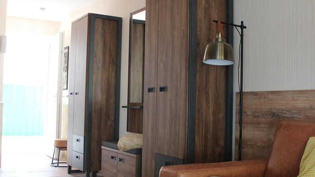 A modern room with a wooden wardrobe, a sofa, a small table, and a lamp. - 2-zi.-fewo im EG für 3 Pers. mit Wlan (Graal-Müritz)