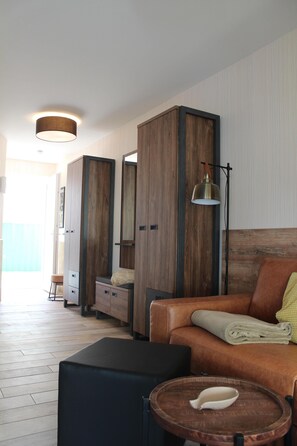 Une chambre moderne avec une armoire en bois, un canapé, une petite table et une lampe.