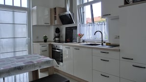 Una cocina moderna con armarios blancos, horno empotrado, cafetera y ventana con vistas al exterior.