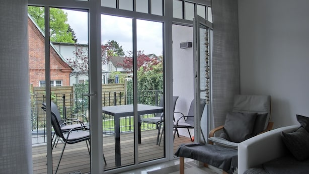 Una sala moderna con un gran ventanal corredero que da a un patio al aire libre.