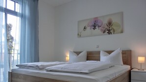 Una habitación de hotel moderna con estructura de cama de madera, ropa de cama blanca y un ventanal con cortinas azules.