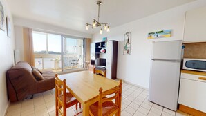 A compact kitchen with a dining table, chairs, a refrigerator, and a microwave.