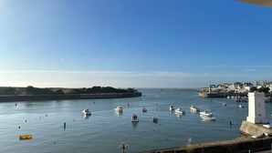 A harbor with boats, a lighthouse, and buildings along the shore.