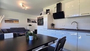 Une cuisine moderne avec des meubles blancs, un plan de travail noir et un coin repas comprenant une table et des chaises.