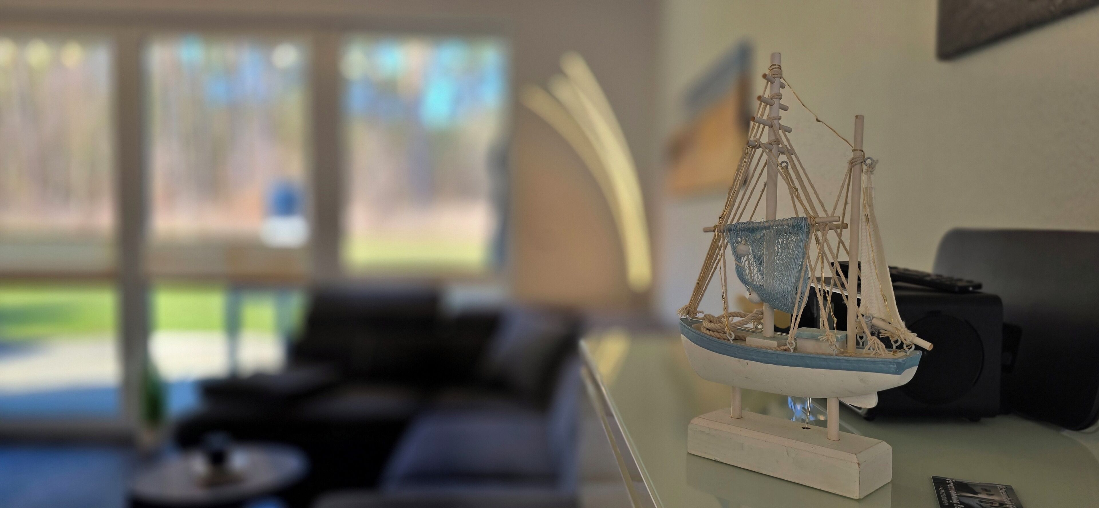 A model ship on a stand in a room with a couch and a table.