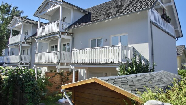 A multi-story residential building with balconies, a wooden deck, and a brick wall. - 2-zi-fewo für 3 Pers. Wlan, Strandnah (Graal-Müritz)