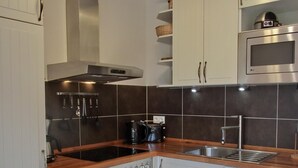 A modern kitchen with white cabinets, a stainless steel oven, a microwave, and a wooden countertop. - 2-zi-fewo für 3 Pers. Wlan, Strandnah (Graal-Müritz)