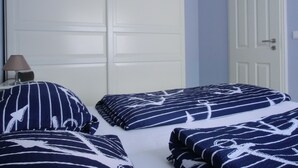 A bedroom with two beds, a nightstand with a lamp, and a white door. - 2-zi-fewo für 3 Pers. Wlan, Strandnah (Graal-Müritz)