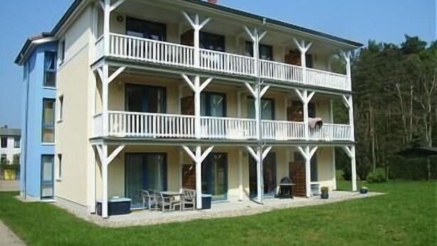 A two-story building with a balcony on each floor, a covered front porch, and a small outdoor seating area. - Modern 2-room vacation apartment for 3 people with bicycles and WLAN (Graal-Müritz)