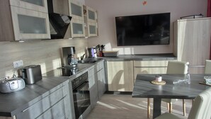 Una cocina moderna con electrodomésticos integrados, un comedor y un televisor de pantalla plana grande.