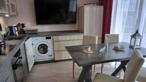 Una cocina moderna con lavadora, una mesa de comedor con sillas y un televisor montado en la pared.