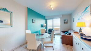 A modern living room with a dining area, a sofa, a coffee table, and a TV. - Le Concorde, appartement face mer (Saint-Gilles-Croix-de-Vie)