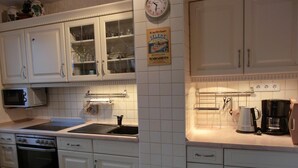 Une cuisine avec des meubles blancs, un four à micro-ondes, une cuisinière, un évier et une machine à café.