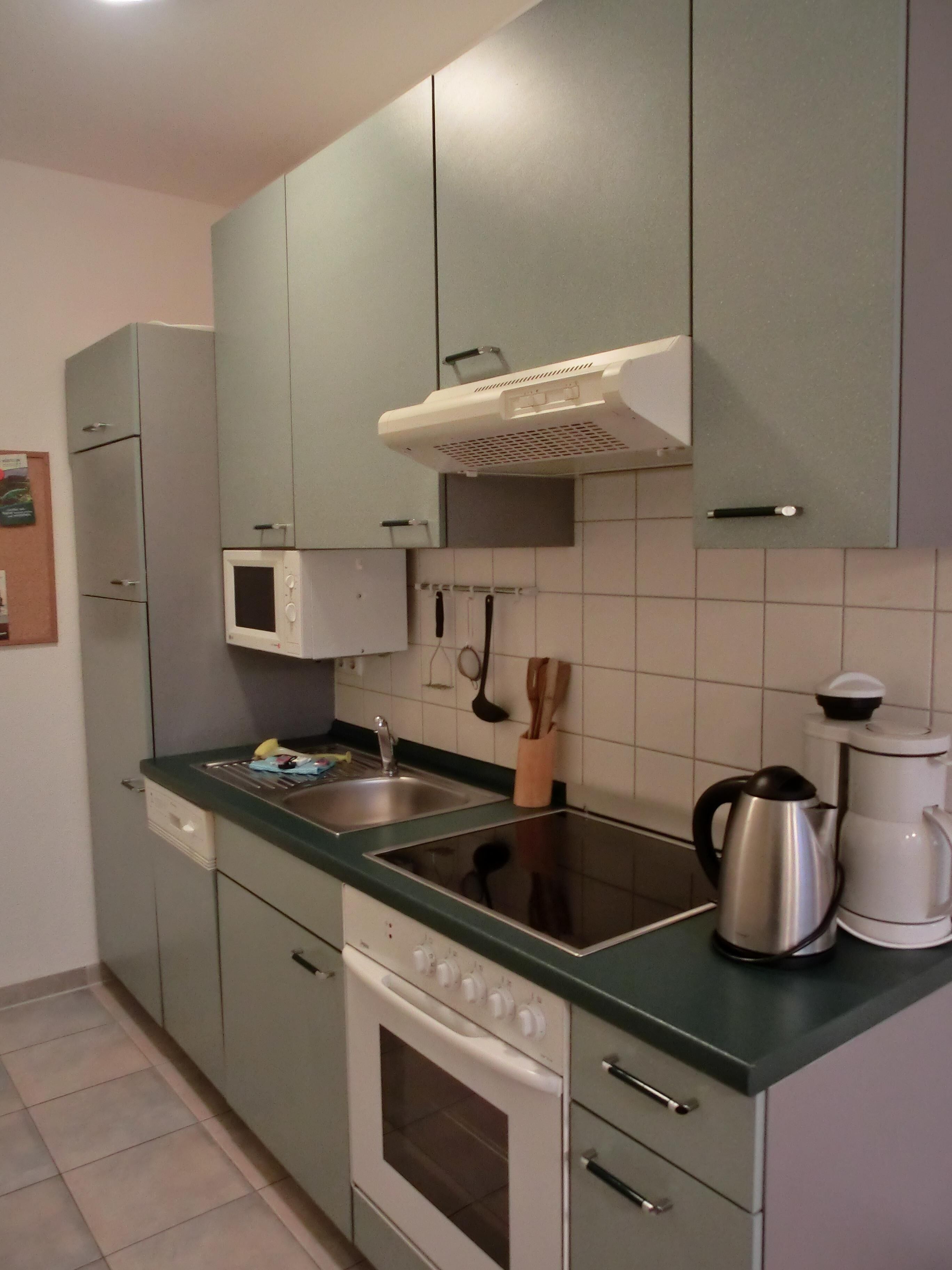 Kompakti keittiö, jossa on mikroaaltouuni, liesi ja kahvinkeitin.