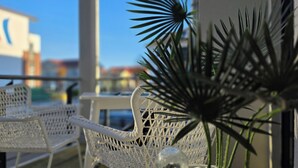 Un balcon avec des chaises en osier peintes en blanc et une plante en pot.