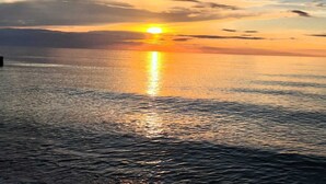 Un coucher de soleil sur une mer calme, avec un horizon dégagé.