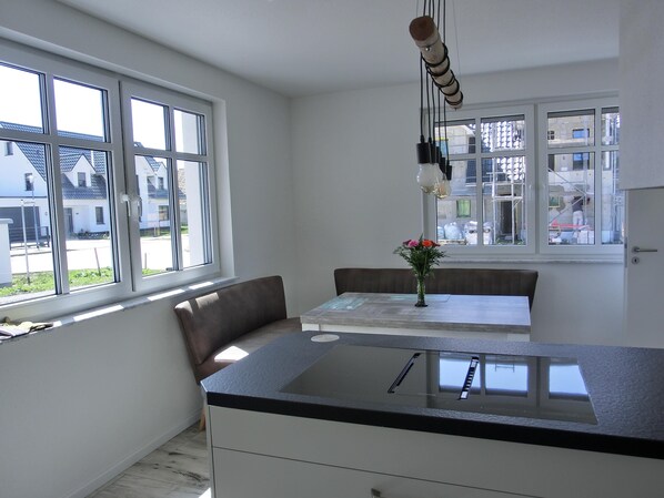 Une cuisine moderne dotée d’un grand îlot central, d’une table à manger avec des chaises et d’un vase rempli de fleurs.