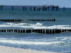A pier extending into the ocean with waves crashing against wooden barriers.