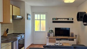 A compact living space with a kitchenette, a flat-screen TV, and a cozy seating area.