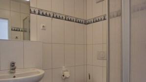 Et badeværelse med en hvid vask, toilet og fliserede vægge.