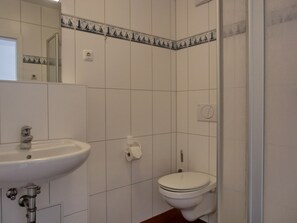 A bathroom with a white sink, toilet, and tiled walls.