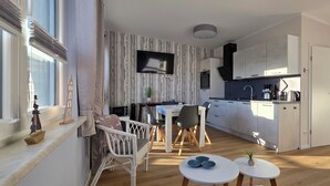 Een moderne keuken met witte kasten, een zwart aanrecht en een ingebouwde oven. Er is een eethoek met een witte tafel en stoelen, en een klein rond tafeltje met decoratieve objecten.