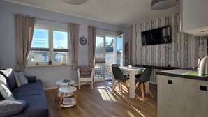 Een moderne woonkamer met een bank, een klein rond tafeltje met een ananas, en een eethoek met stoelen.