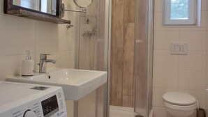 A bathroom with a washing machine, a sink, a glass-enclosed shower, and a toilet. - 2-zimmer-fewo für 4 Pers. mit Wlan (Graal-Müritz)