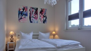 A bedroom with a white bed, two bedside lamps, and abstract art on the wall. - 2-zimmer-fewo für 4 Pers. mit Wlan (Graal-Müritz)