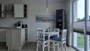 A modern kitchen with a dining table and chairs, a coffee maker, and a painting on the wall. - 2-zimmer-fewo für 4 Pers. mit Wlan (Graal-Müritz)
