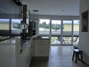A modern kitchen with a large window, a dining area with a table and chairs, and a small stool.