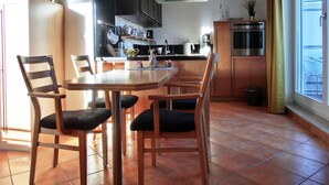 Una cocina moderna con comedor, que incluye una isla central, sillas de madera y un amplio ventanal con cortinas.