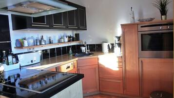 Eine moderne Küche mit schwarzen Schränken, einer Edelstahl-Dunstabzugshaube, einem Einbauofen und einer Kaffeemaschine.