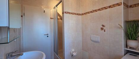 A bathroom with a bathtub, a glass shower enclosure, a toilet, and a sink.