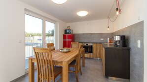 Een moderne keuken met een houten eettafel, een rode koelkast en roestvrijstalen apparatuur.